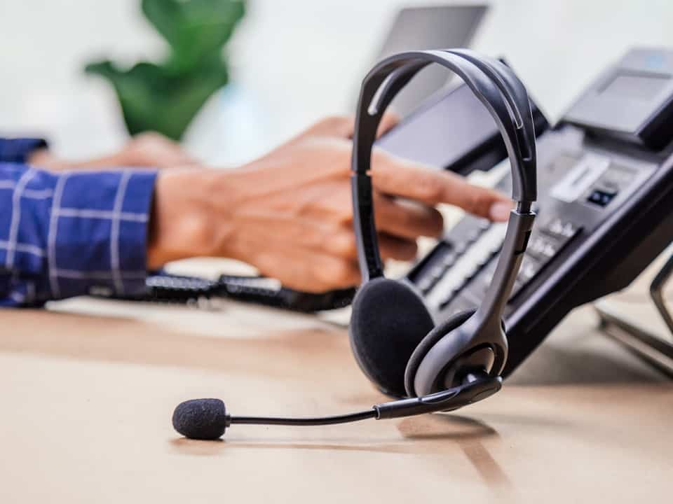 hand pressing buttons on a phone with headset